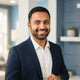 A friendly South Asian man smiling in a professional studio headshot for a customer testimonial.